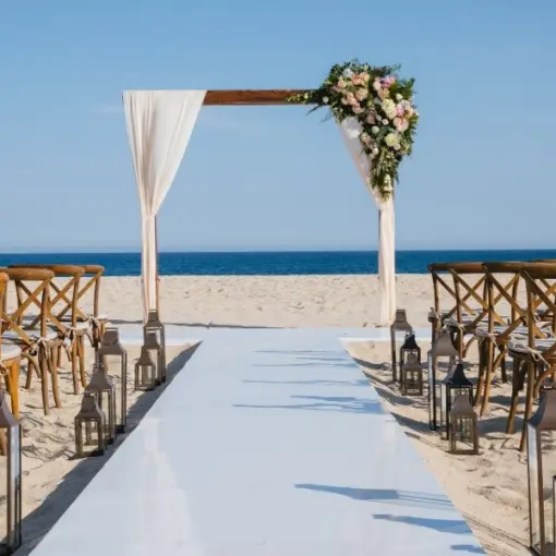 Beachfront wedding ceremony with wooden arch and cross-back chairs at Barcelo Gran Faro, Cabo San Lucas