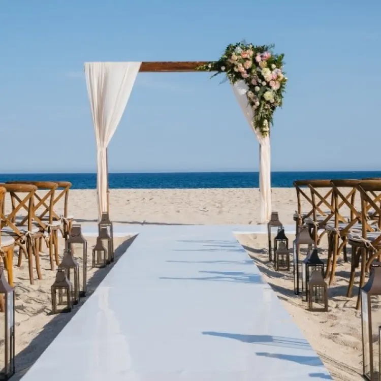 Beachfront wedding ceremony with wooden arch and cross-back chairs at Barcelo Gran Faro, Cabo San Lucas