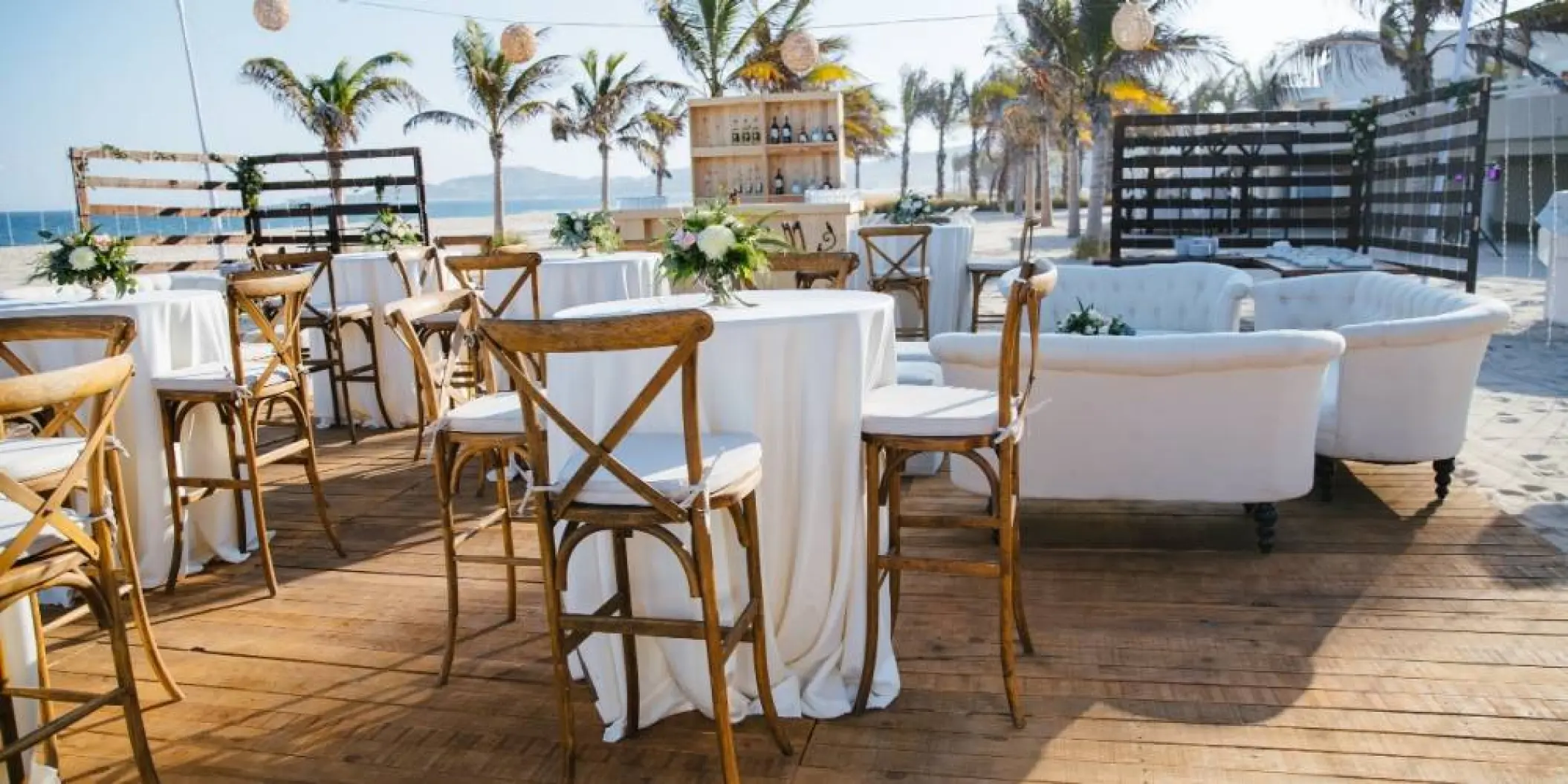 Beachfront wedding reception with wooden deck and white lounge seating at Barcelo Gran Faro, Cabo San Lucas