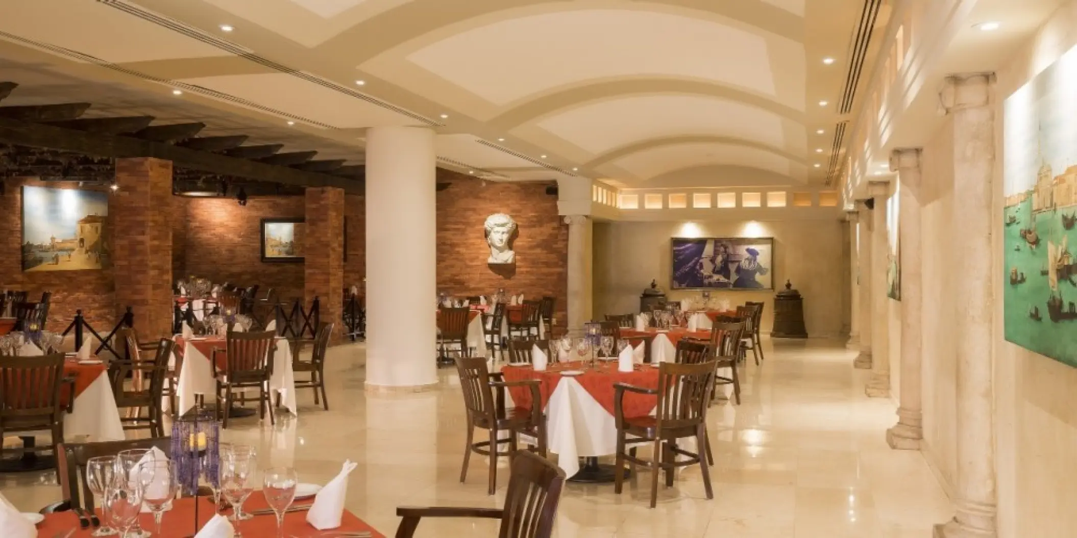 Indoor restaurant dining room with white and orange linens at Barcelo Gran Faro, Cabo San Lucas