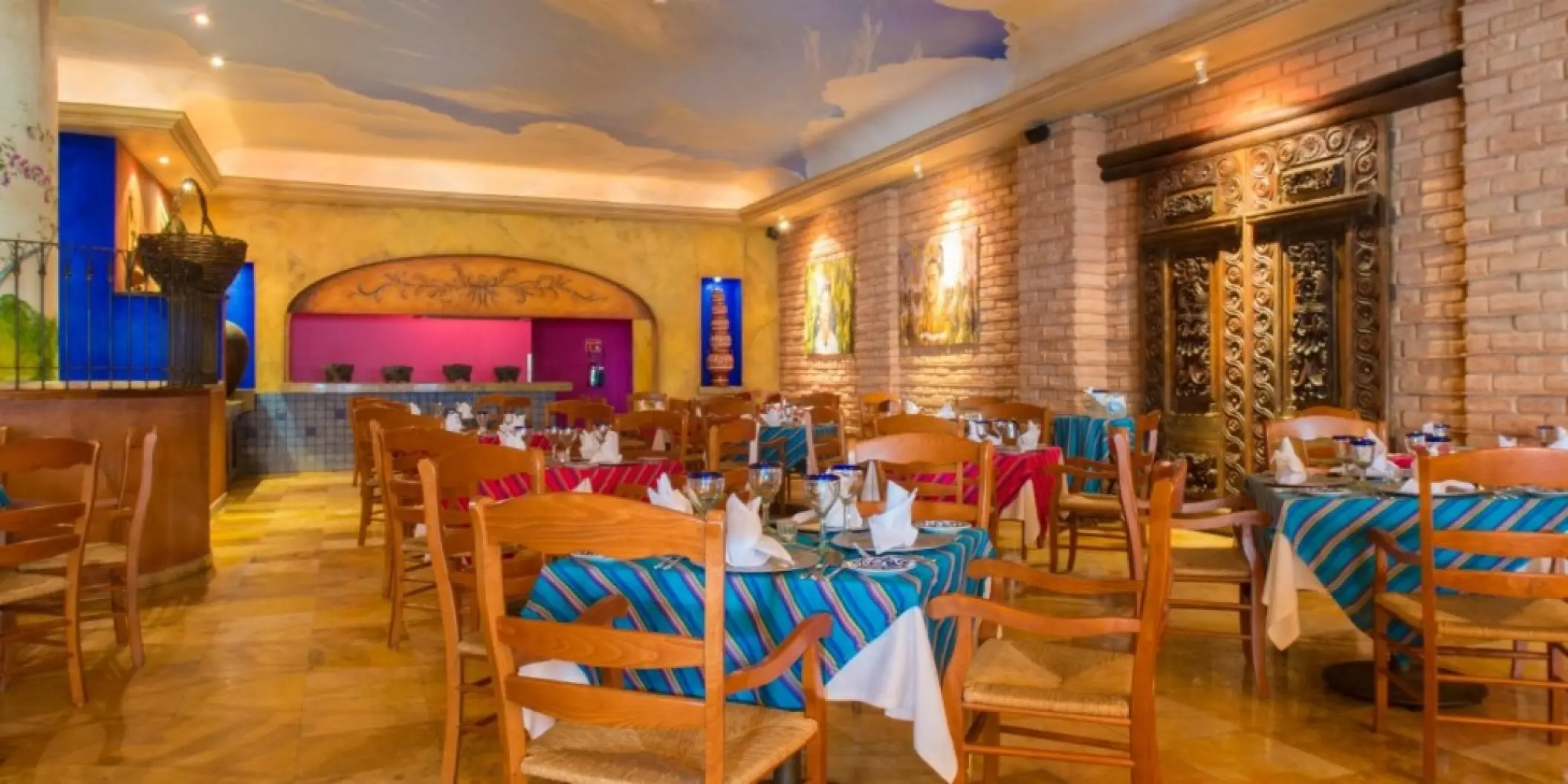Indoor restaurant with striped linens and brick walls at Barcelo Gran Faro, Cabo San Lucas
