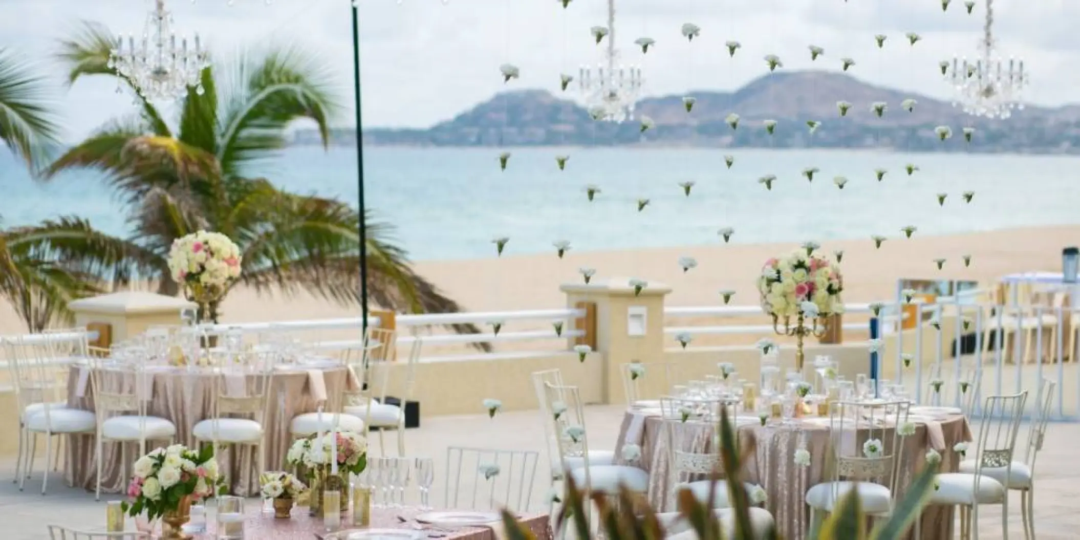 Terrace wedding reception with floral centerpieces and hanging crystals at Barcelo Gran Faro, Cabo San Lucas