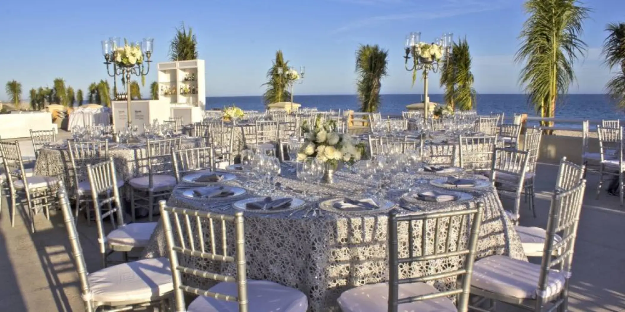 Terrace wedding reception with silver chairs and lace linens at Barcelo Gran Faro, Cabo San Lucas