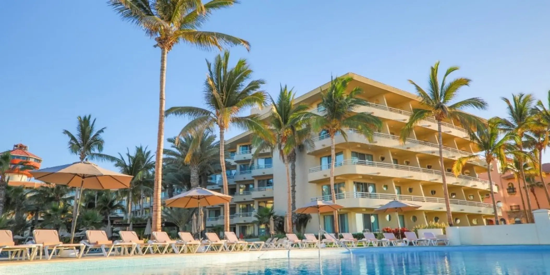 Barcelo Gran Faro Los Cabos pool deck with lounge chairs and palm trees, Cabo San Lucas