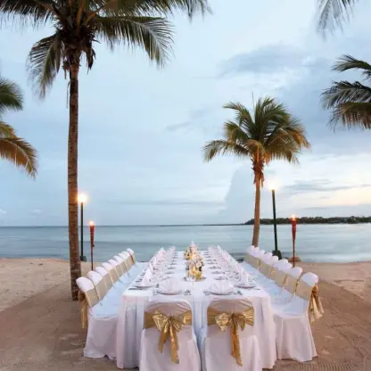 Beachfront wedding reception setup with tiki torches at Barcelo Maya Riviera, Riviera Maya