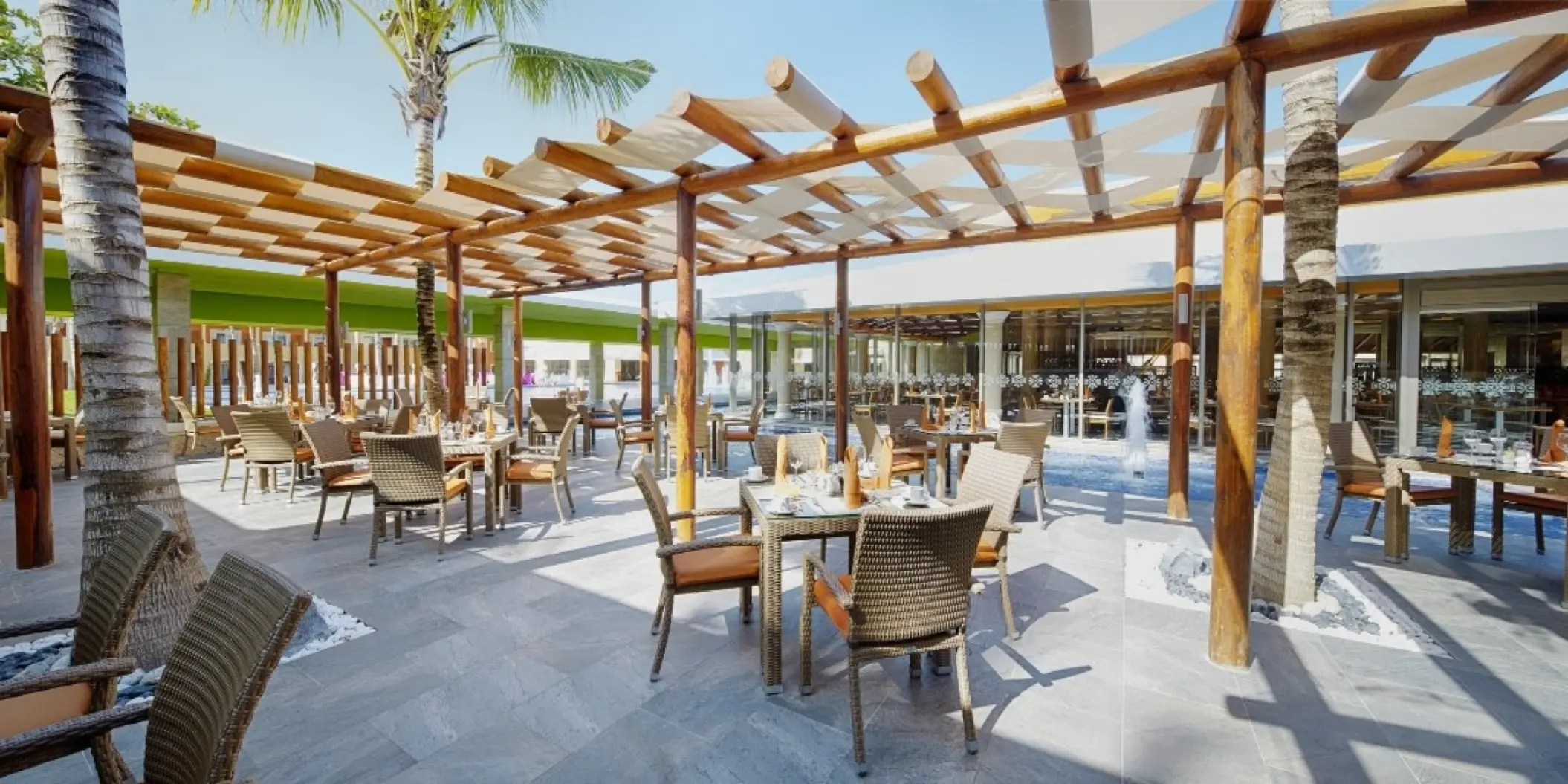 Outdoor restaurant terrace with a wooden pergola at Barcelo Maya Colonial, Riviera Maya