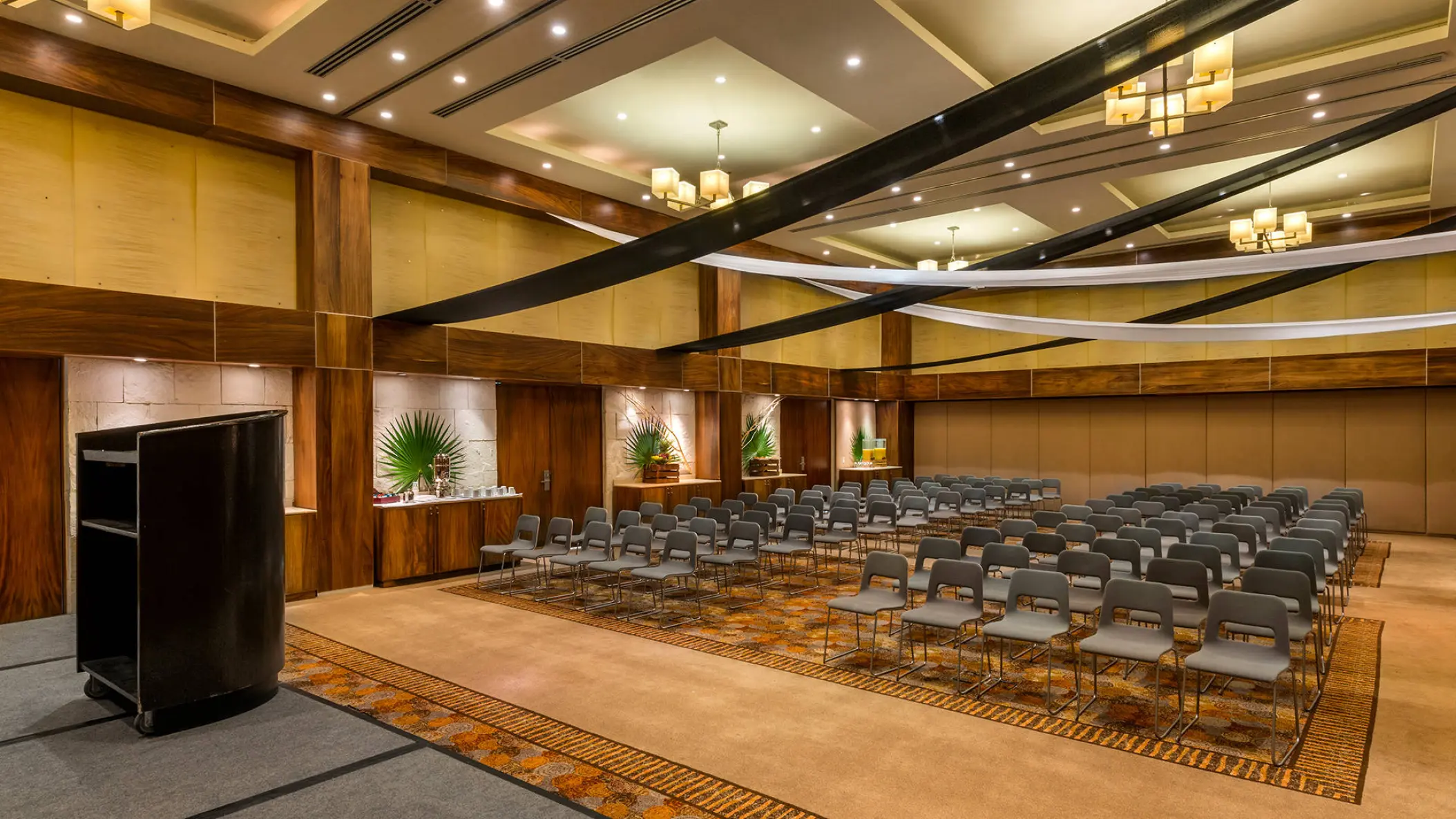 Indoor wedding ceremony room with rows of chairs and a podium at Barcelo Maya Riviera, Playa Del Carmen