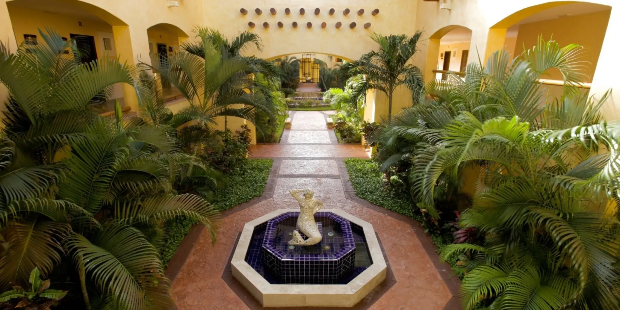 Barcelo Maya Tropical courtyard with lush palm trees and a central water fountain, Riviera Maya