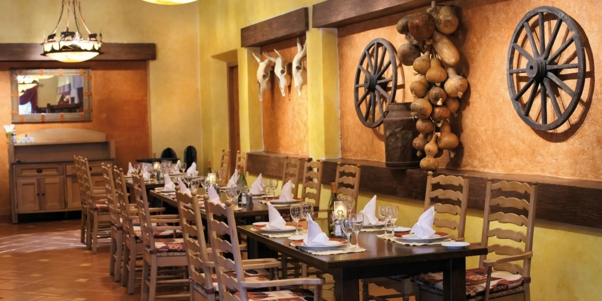 Rustic restaurant dining area with wooden wheels and skull decor at Barcelo Maya Tropical, Riviera Maya
