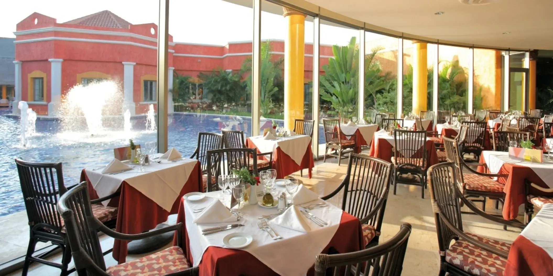 Indoor restaurant with floor-to-ceiling windows overlooking a fountain pool at Barcelo Maya Tropical, Riviera Maya