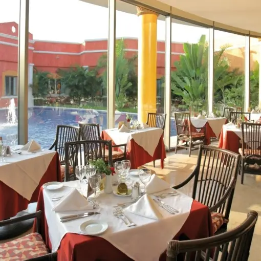 Indoor restaurant with floor-to-ceiling windows overlooking a fountain pool at Barcelo Maya Tropical, Riviera Maya
