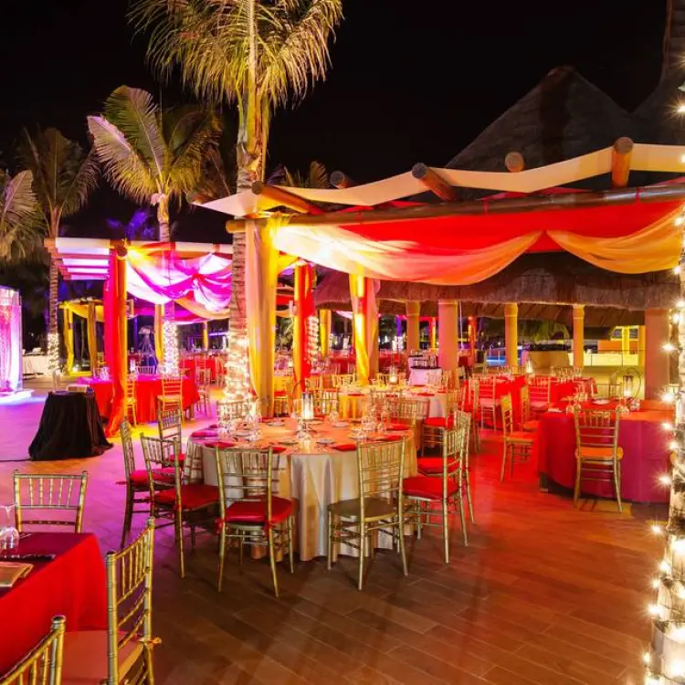 Outdoor wedding reception with red linens and fairy lights at night at Barcelo Maya Riviera, Riviera Maya