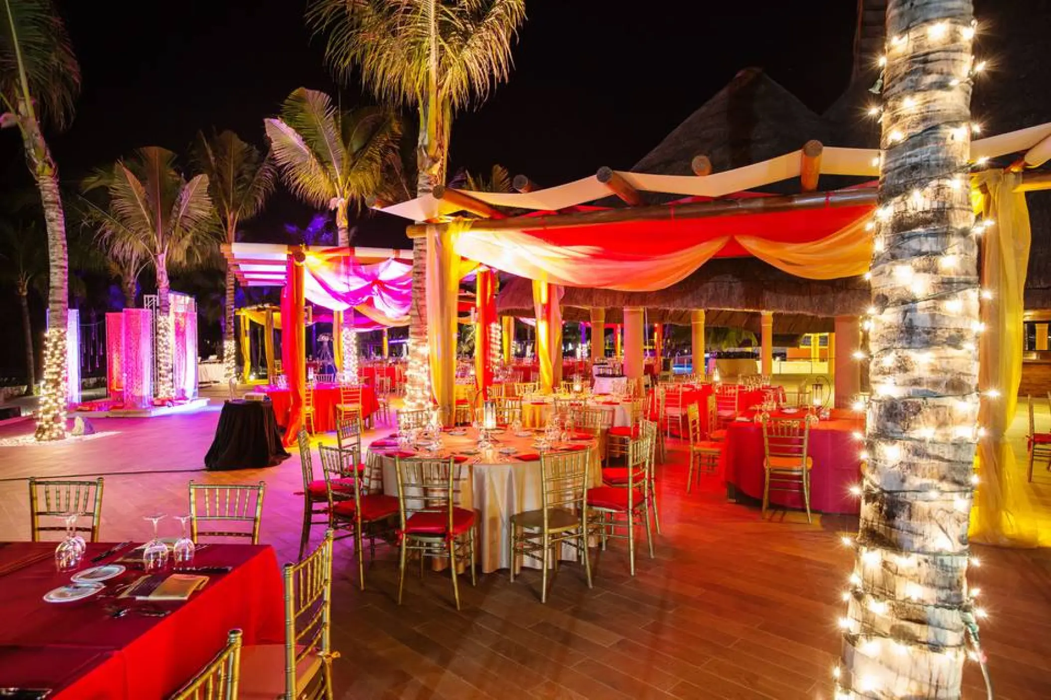 Outdoor wedding reception with red linens and fairy lights at night at Barcelo Maya Riviera, Riviera Maya