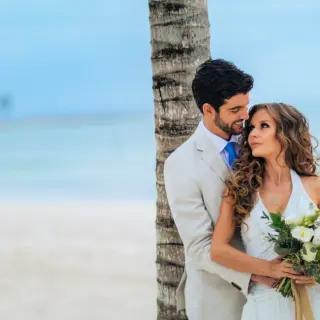 Newlywed couple posing by a palm tree at Barcelo Maya Riviera, Riviera Maya