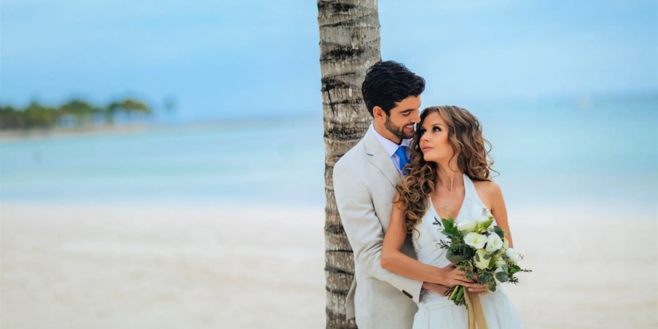 Newlywed couple posing by a palm tree at Barcelo Maya Riviera, Riviera Maya