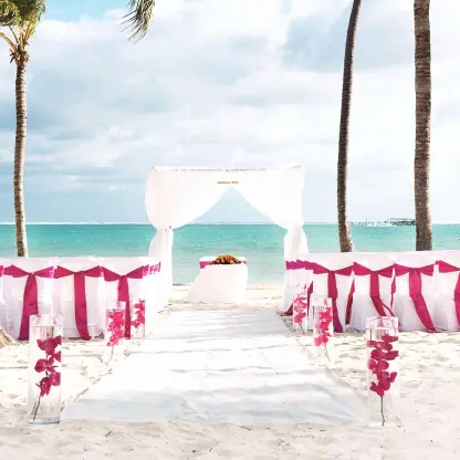 Beachfront wedding ceremony with pink chair sashes and a white canopy at Barcelo Maya Riviera, Riviera Maya