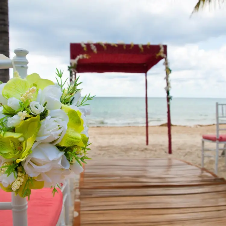 Beachfront wedding ceremony with a red gazebo and floral chair decor at Blue Diamond Luxury, Playa Del Carmen