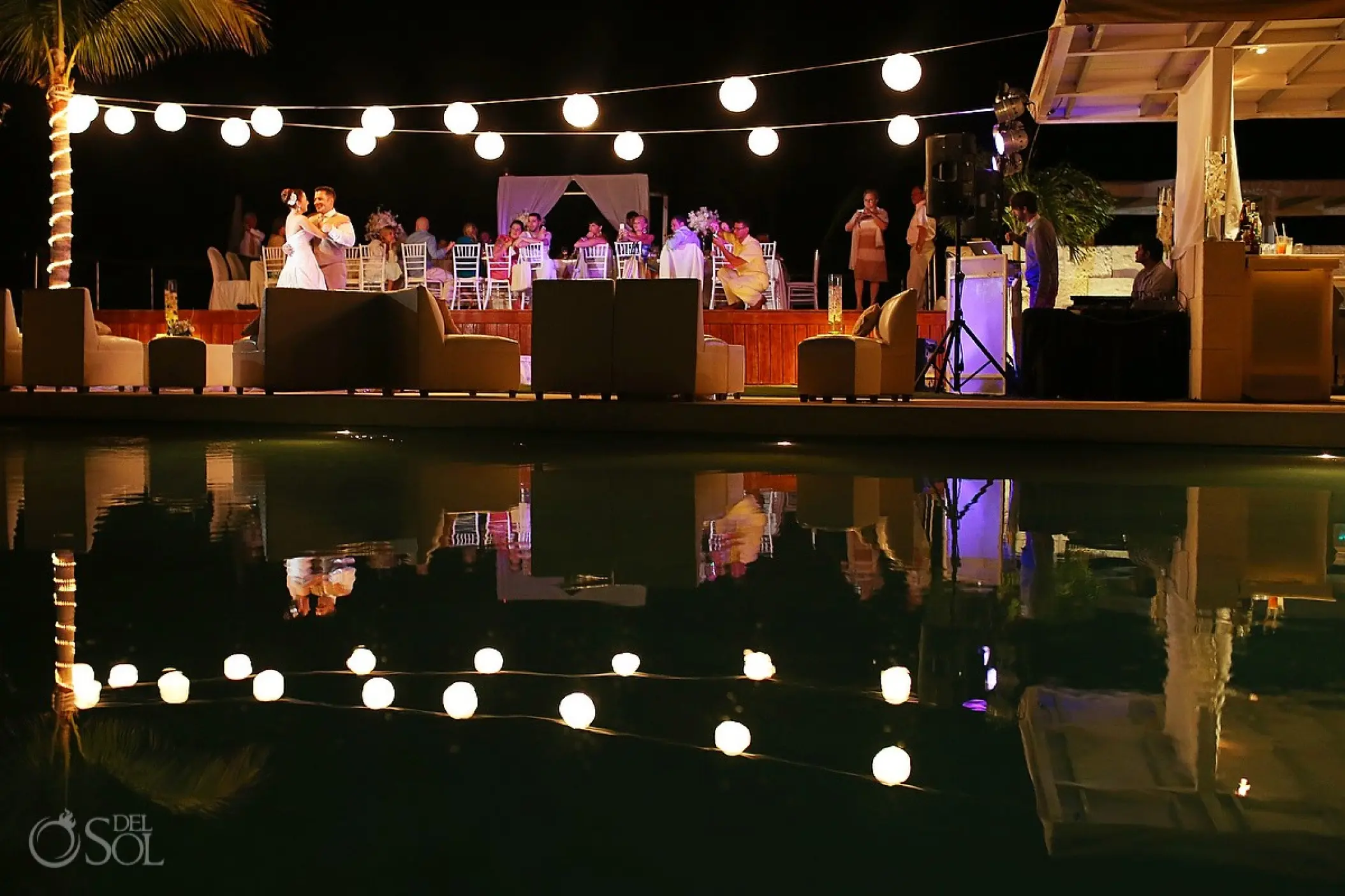 Evening wedding reception under string lights with pool reflection at Blue Diamond, Playa Del Carmen