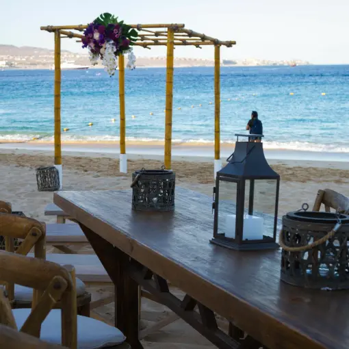 Beachfront wedding reception setup with wooden table and bamboo gazebo at Breathless Cabo San Lucas