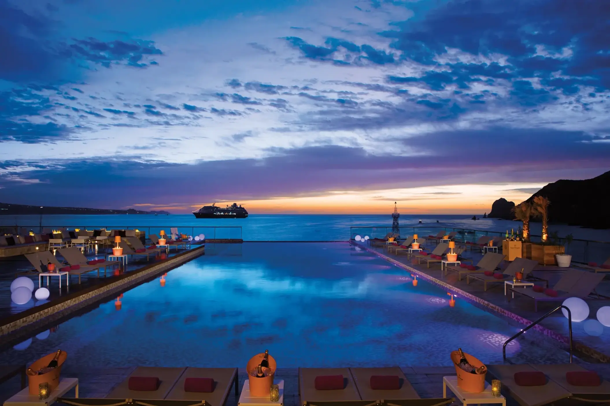 Breathless Cabo San Lucas infinity pool and lounge area at sunset with a cruise ship in the distance, Cabo San Lucas