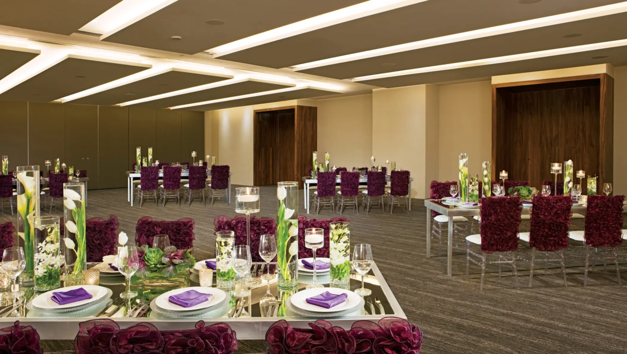 Ballroom wedding reception at Breathless Cabo San Lucas with purple chair covers and floral centerpieces