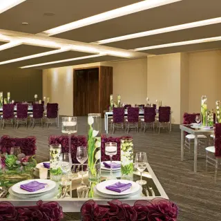 Ballroom wedding reception at Breathless Cabo San Lucas with purple chair covers and floral centerpieces