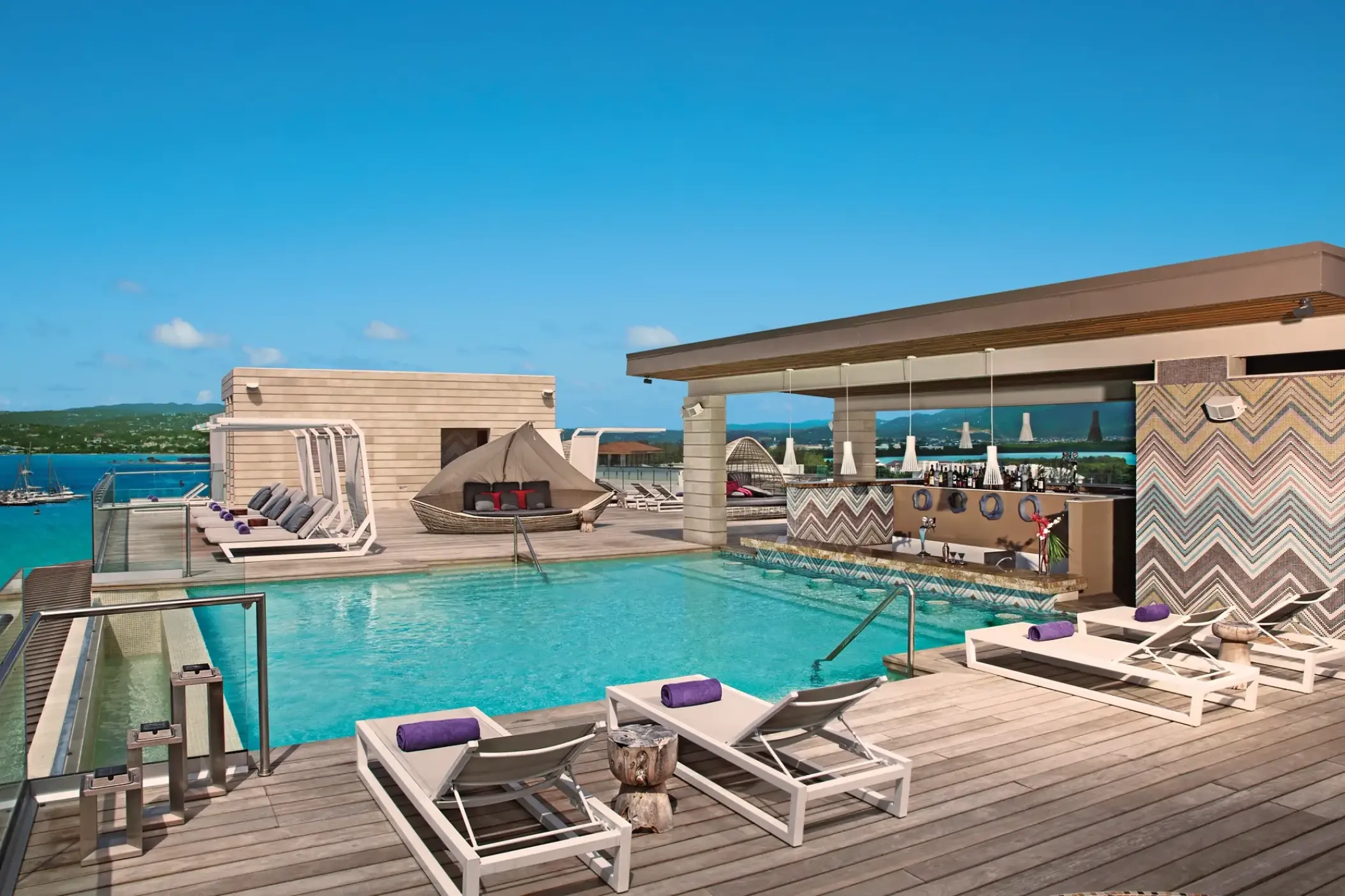 Rooftop infinity pool and bar with lounge chairs at Breathless Montego Bay