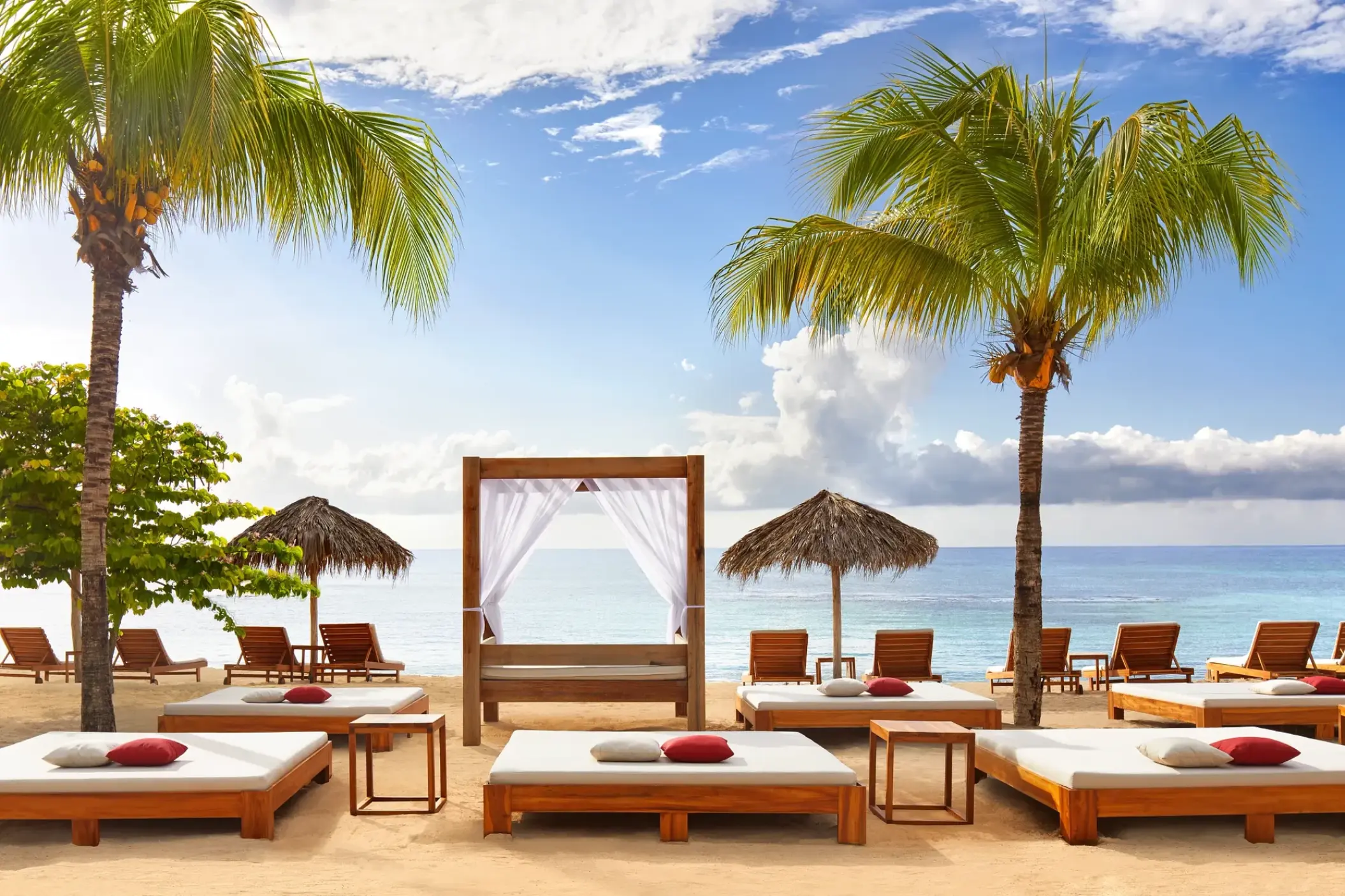 Beach club lounge beds and cabanas under palm trees at Breathless Montego Bay