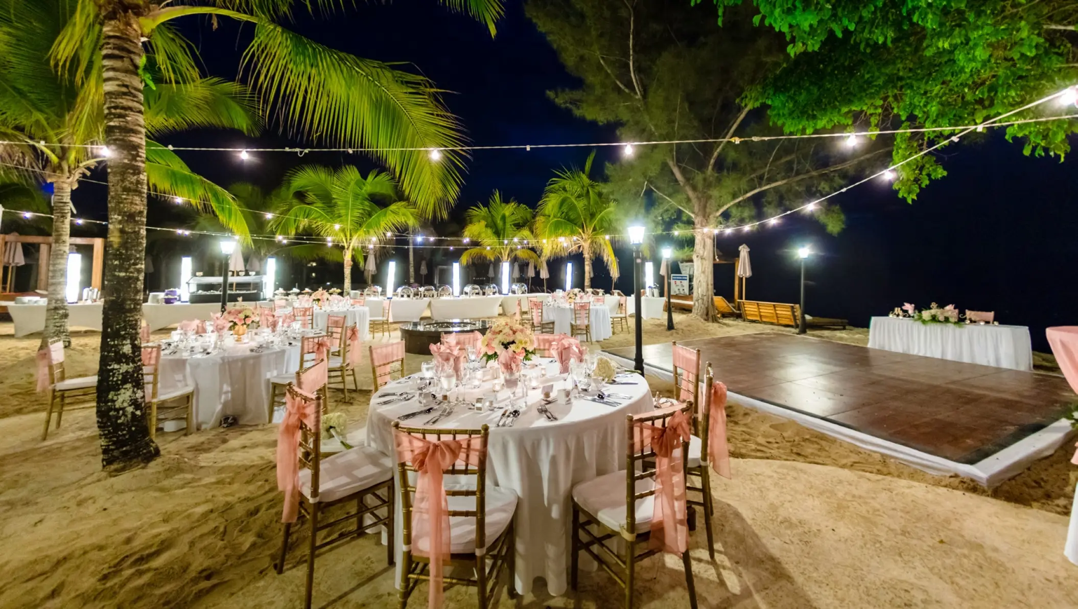 Nighttime beach wedding reception setup with string lights and a dance floor at Breathless Montego Bay