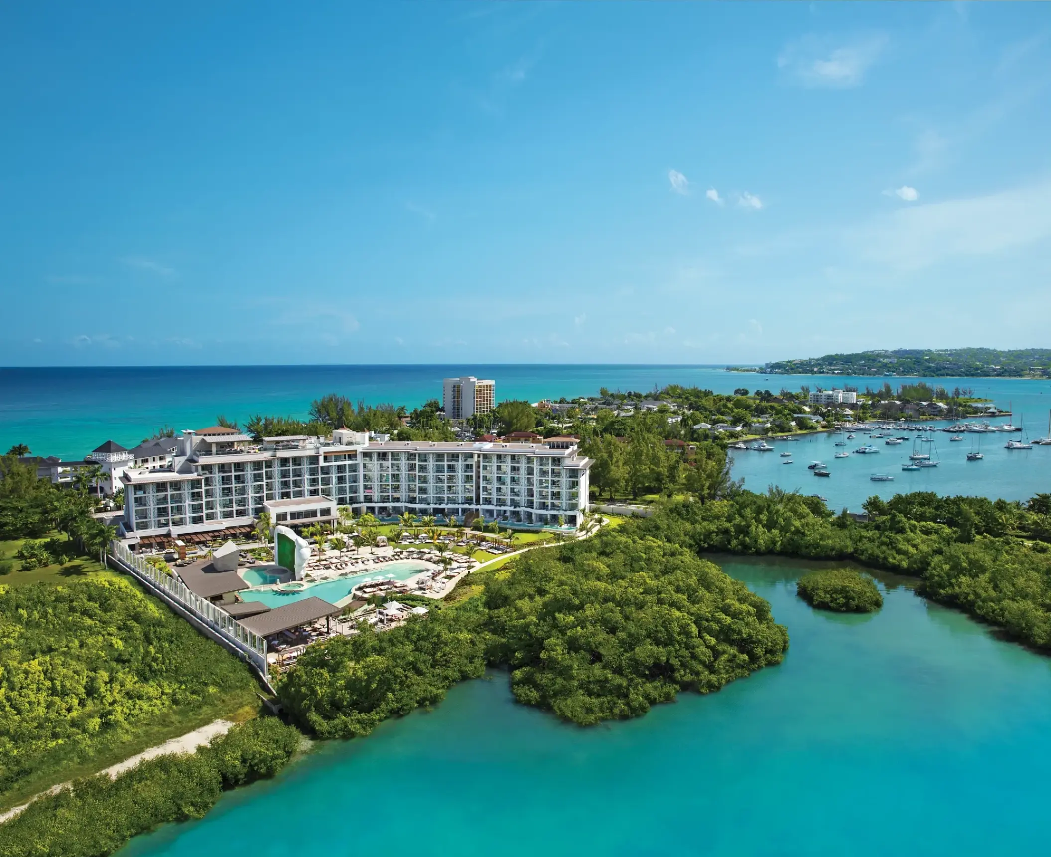 Aerial view of Breathless Montego Bay buildings and pools surrounded by tropical greenery and turquoise water, Jamaica