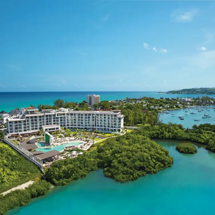 Aerial view of Breathless Montego Bay buildings and pools surrounded by tropical greenery and turquoise water, Jamaica