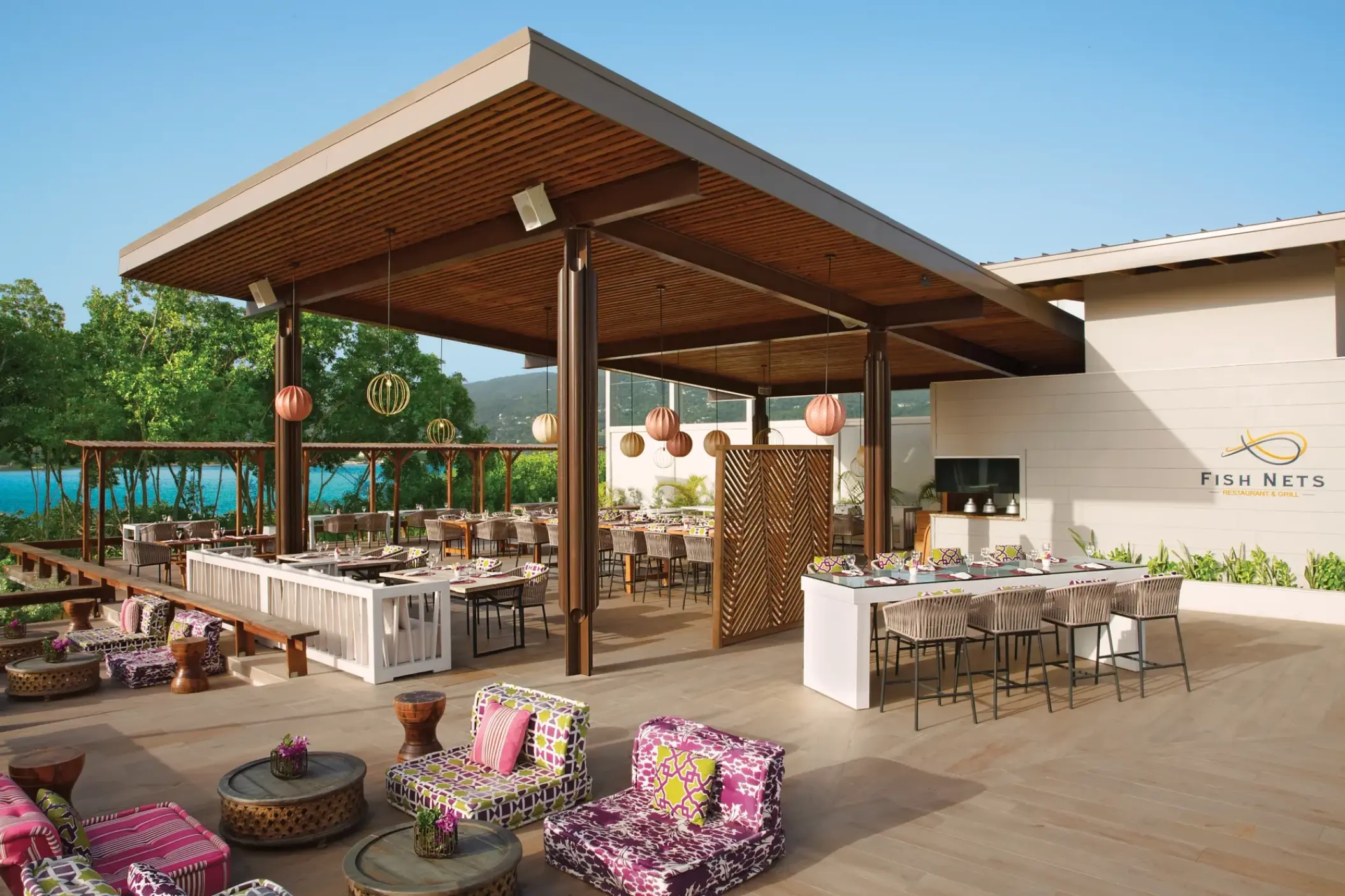 Open-air Fish Nets restaurant with colorful lounge seating and wooden canopy at Breathless Montego Bay