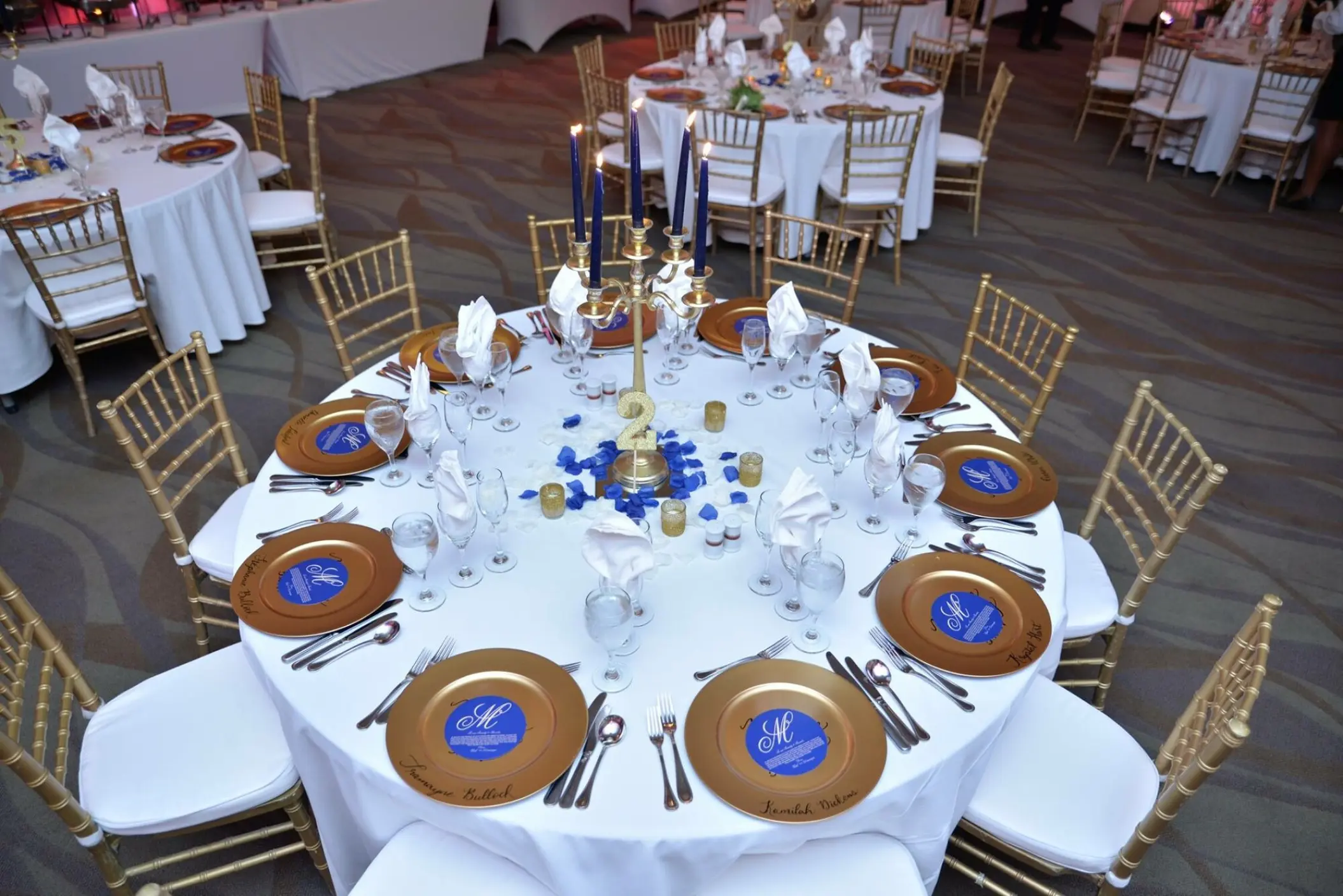 Indoor wedding reception at Breathless Montego Bay, Jamaica with gold charger plates and blue candle centerpieces
