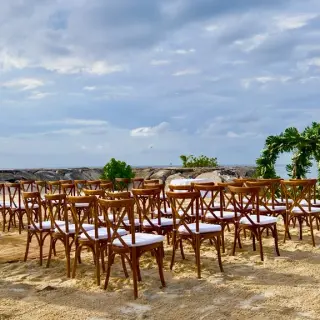 Beachfront wedding ceremony with wooden cross-back chairs and leaf-covered arch at Breathless Montego Bay