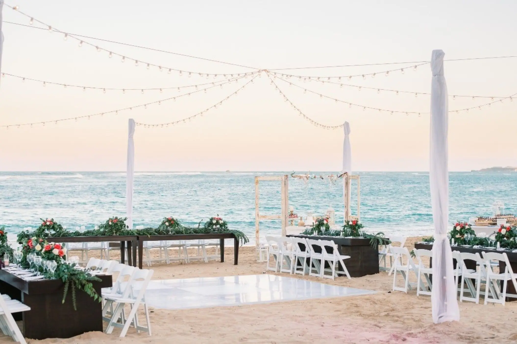 Beachfront wedding reception setup with white dance floor and string lights at Breathless Punta Cana, Punta Cana