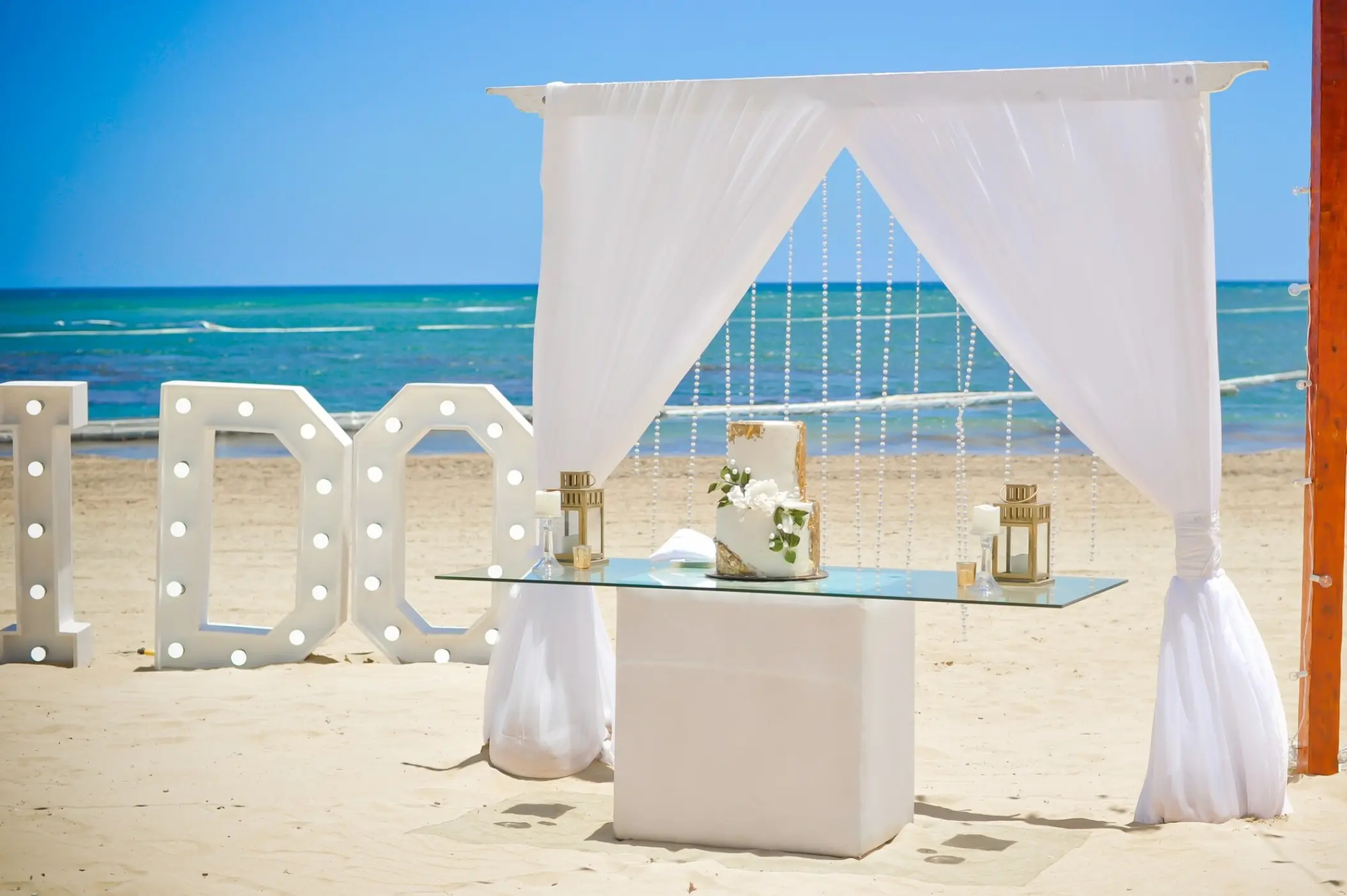 Beachfront wedding setup with cake and I DO letters at Breathless Punta Cana
