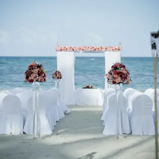 Beachfront wedding ceremony with white chairs and pink floral arch at Breathless Punta Cana, Punta Cana