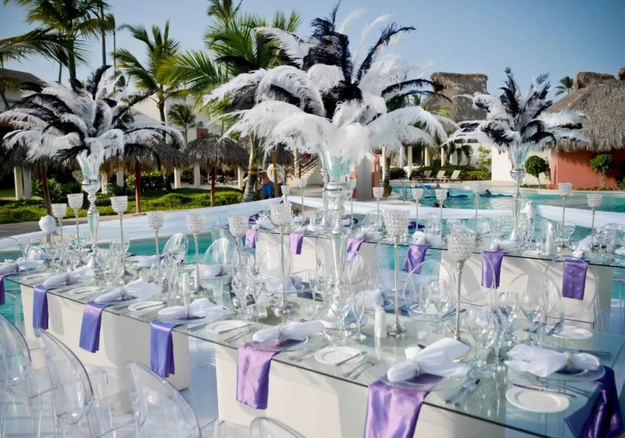 Poolside wedding reception with feather centerpieces and purple napkins at Breathless Punta Cana