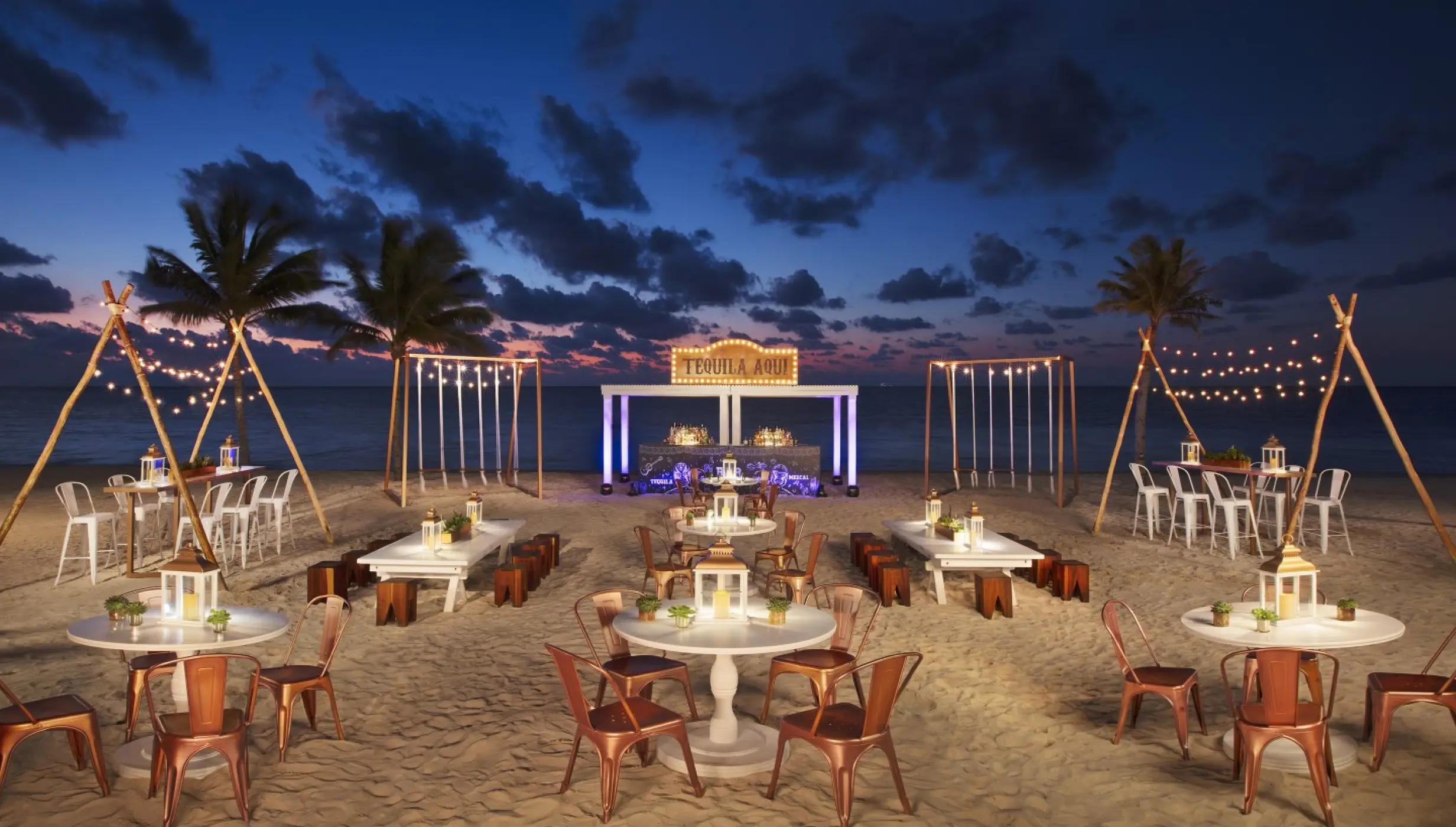 Beachfront wedding reception at Breathless Riviera Cancun with string lights and white tables at sunset, Riviera Maya