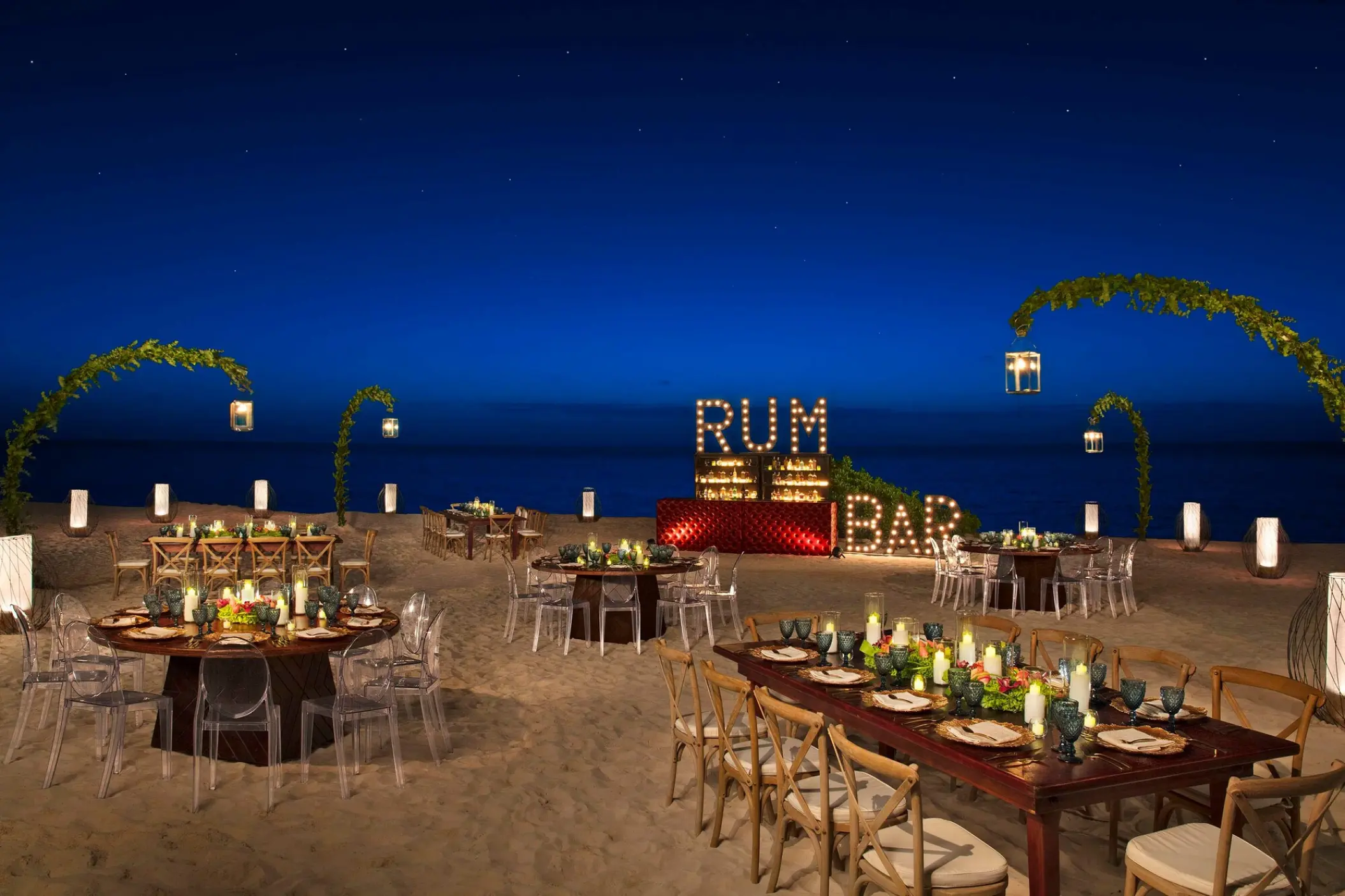 Beach wedding reception with a marquee rum bar and floral arches at Breathless Riviera Cancun, Riviera Maya