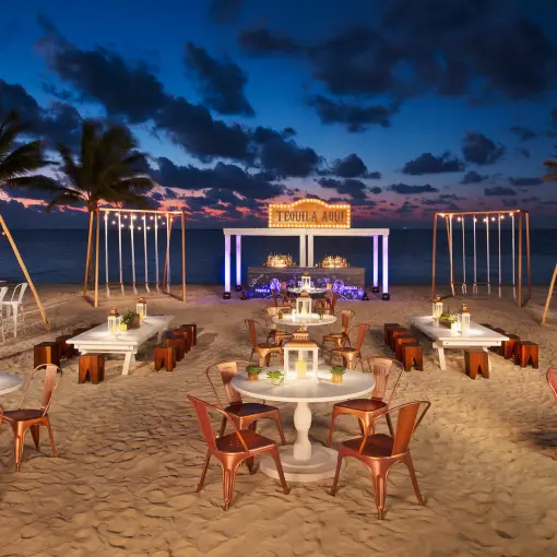 Nighttime beach wedding reception with string lights and white tables at Breathless Riviera Cancun, Riviera Maya