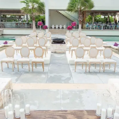 Outdoor wedding ceremony setup with white chairs on a platform over the pool at Breathless Riviera Cancun, Riviera Maya