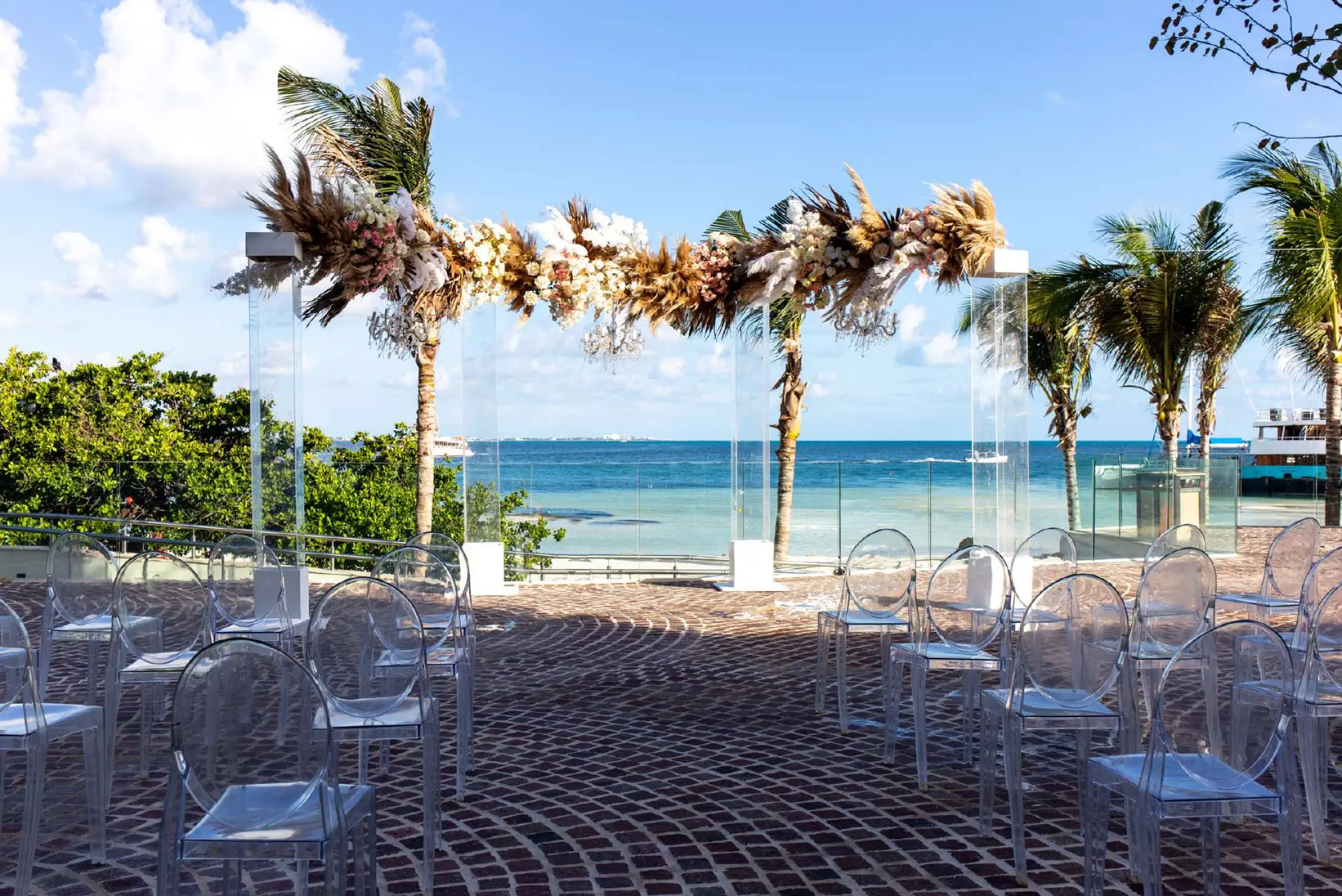 Terrace wedding ceremony with pampas grass arch and ghost chairs at Breathless Cancun Soul, Cancun