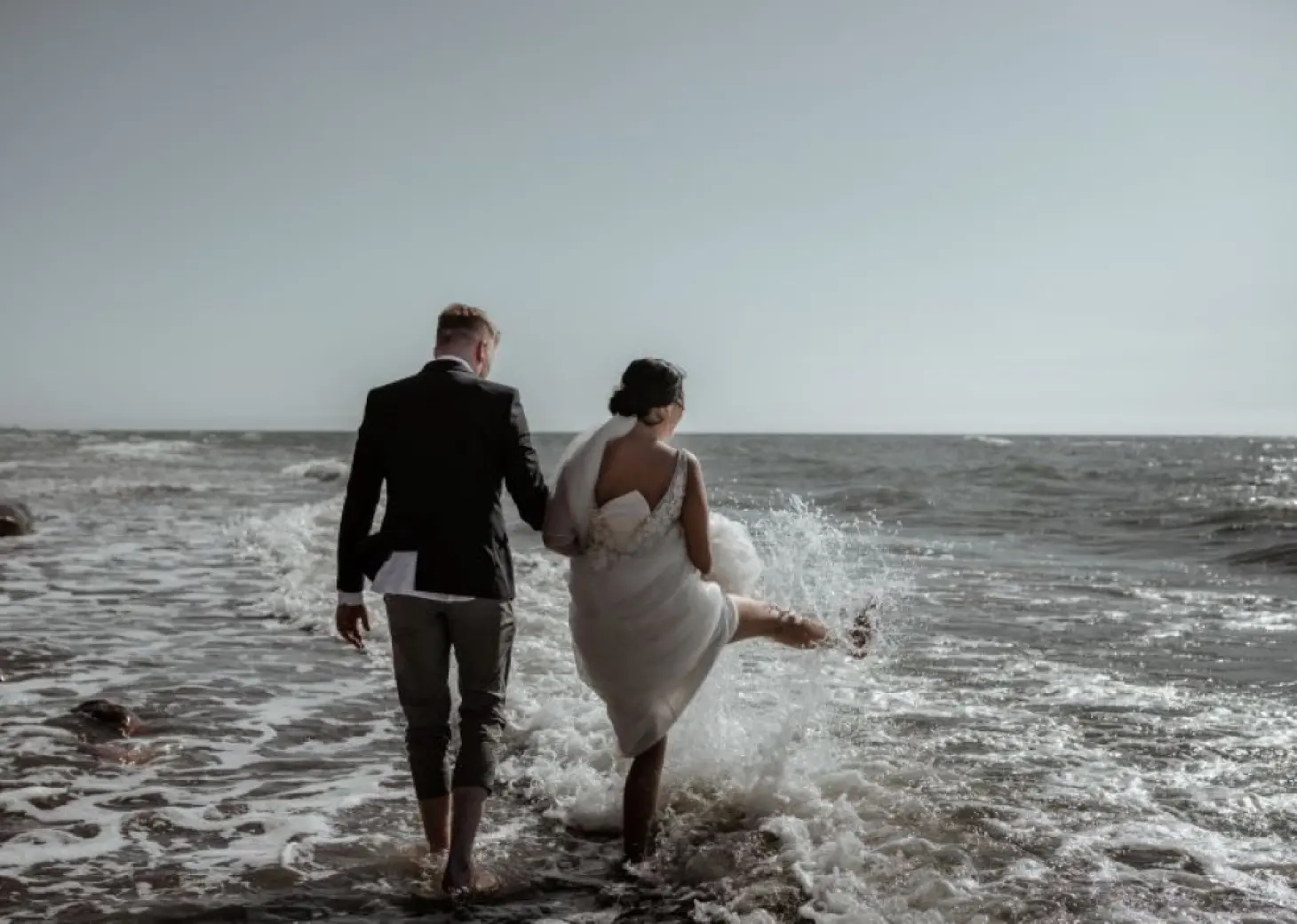 The bride and groom splashing in the waves at Riu Palace Costa Rica, Papagayo