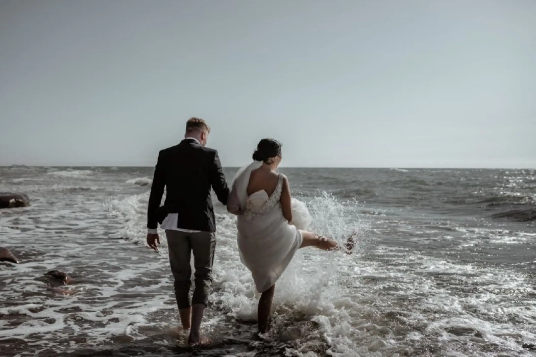 bride and groom playing in the sea