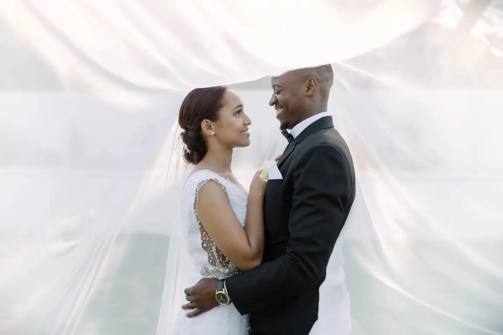 Bride and groom embracing under a wedding veil at Royalton Blue Waters, Montego Bay