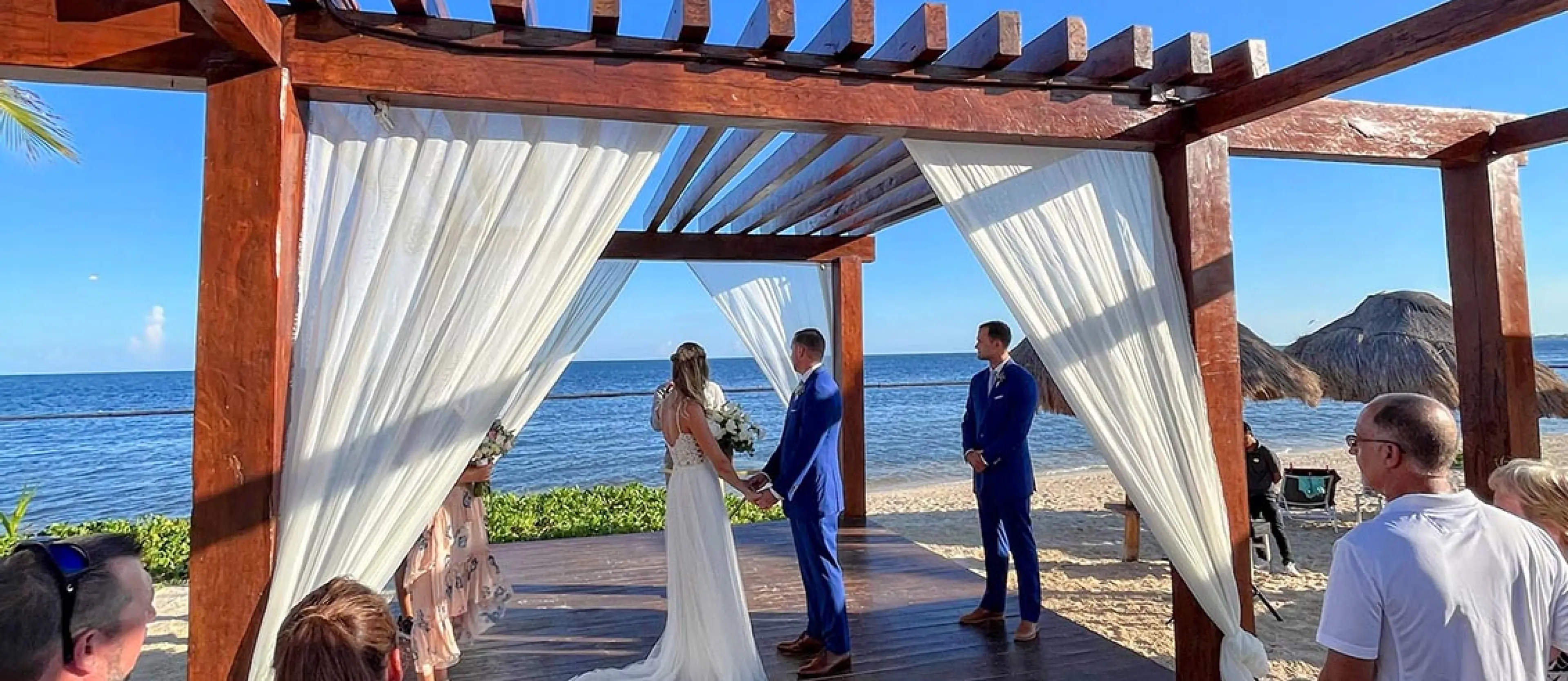Casey & Matt's beach ceremony under a wooden pergola overlooking the ocean