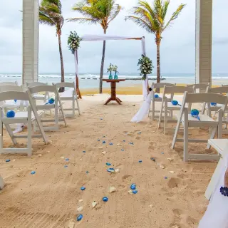 Beachfront wedding ceremony with white chairs and floral arch at Catalonia Grand Costa Mujeres, Cancun