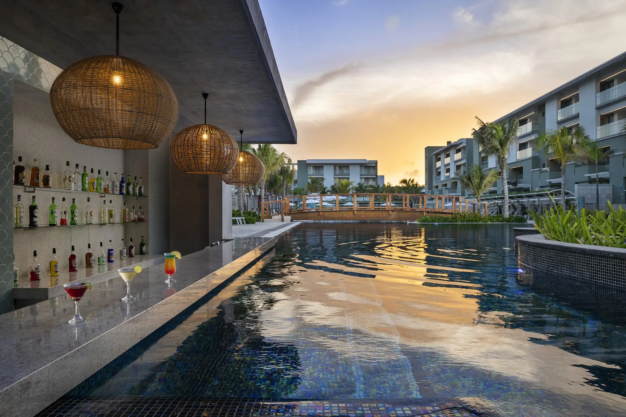 Swim-up bar with wicker pendant lights and sunset reflections in the pool at Catalonia Grand Costa Mujeres, Cancun