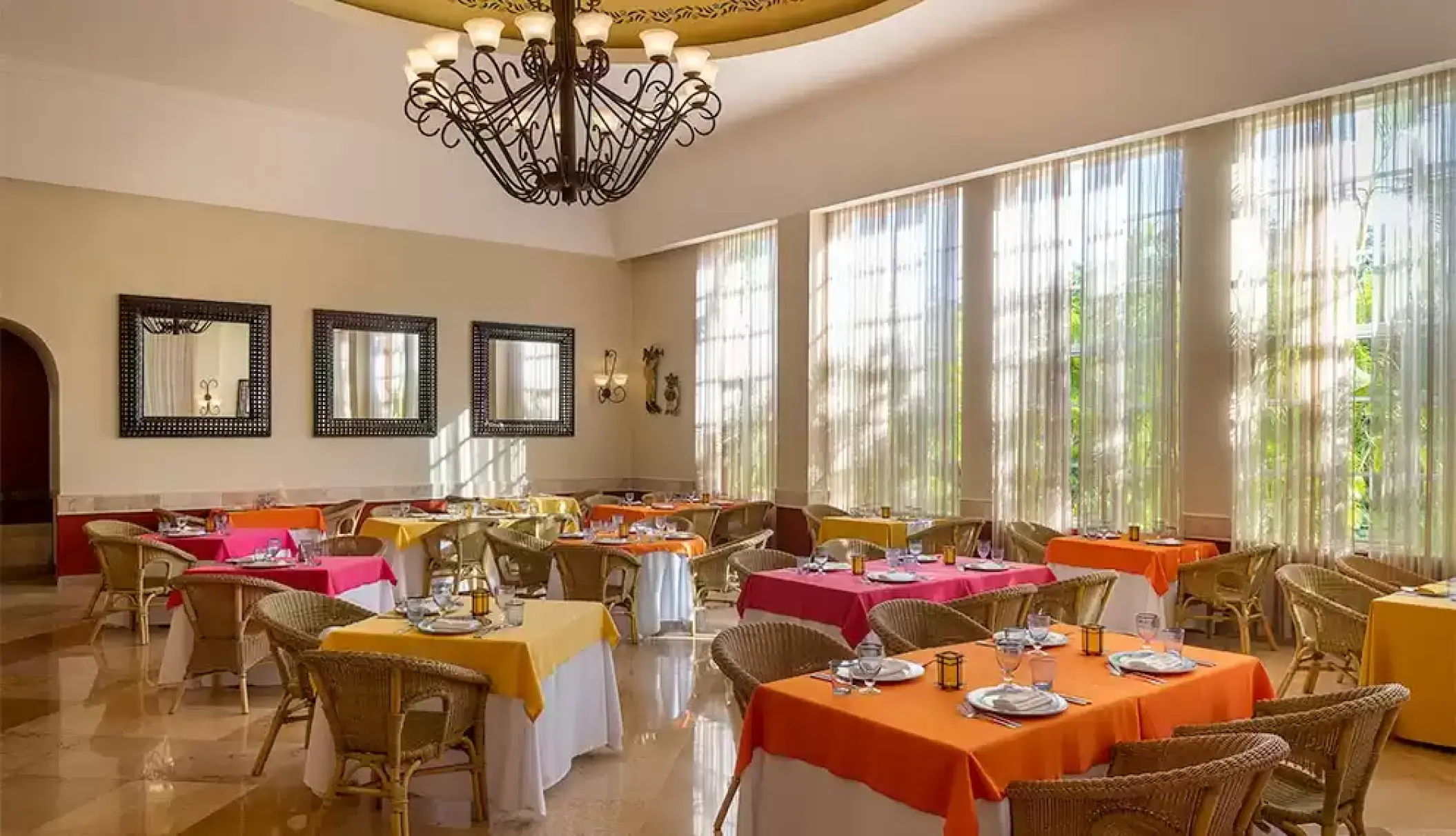 Adelita restaurant with colorful table linens and wrought iron chandelier at Catalonia Royal Tulum